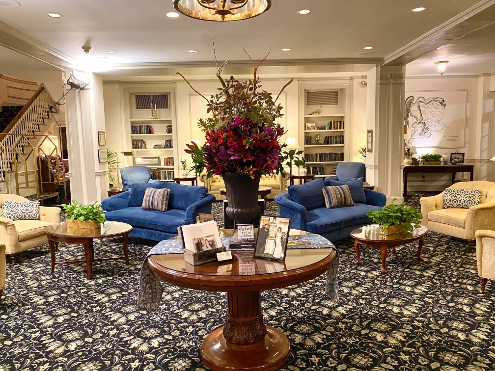 Image of The Lobby at The Hawthorne Hotel with bookcase, velvet chairs and grand floral arrangement. The Hawthorne Hotel,a member of Historic Hotels of America since 1991, located in Salem, Massachusetts