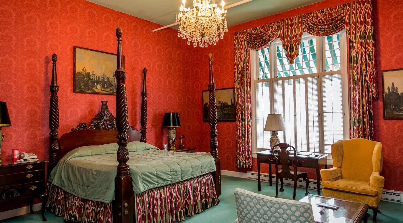 Image of the Signature Suite army green silk covers displayed on four-poster king-size bed and velvet couch. Grand Hotel, a member of Historic Hotels since 2001, dates to 1886. It is located in Mackinac Island, Michigan.