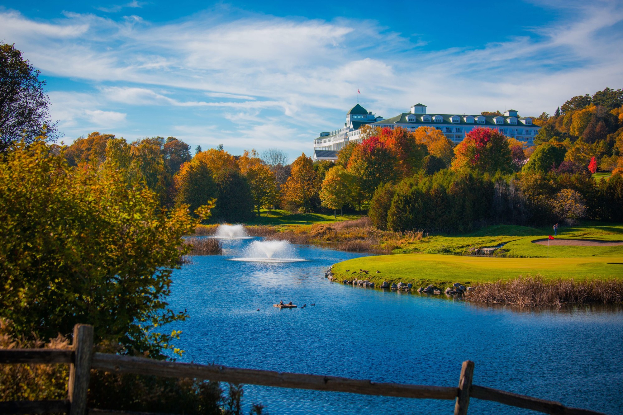 Image of The Jewel Golf Course with fall foliage and water fountains in the lake. Grand Hotel, a member of Historic Hotels since 2001, dates to 1886. It is located in Mackinac Island, Michigan.