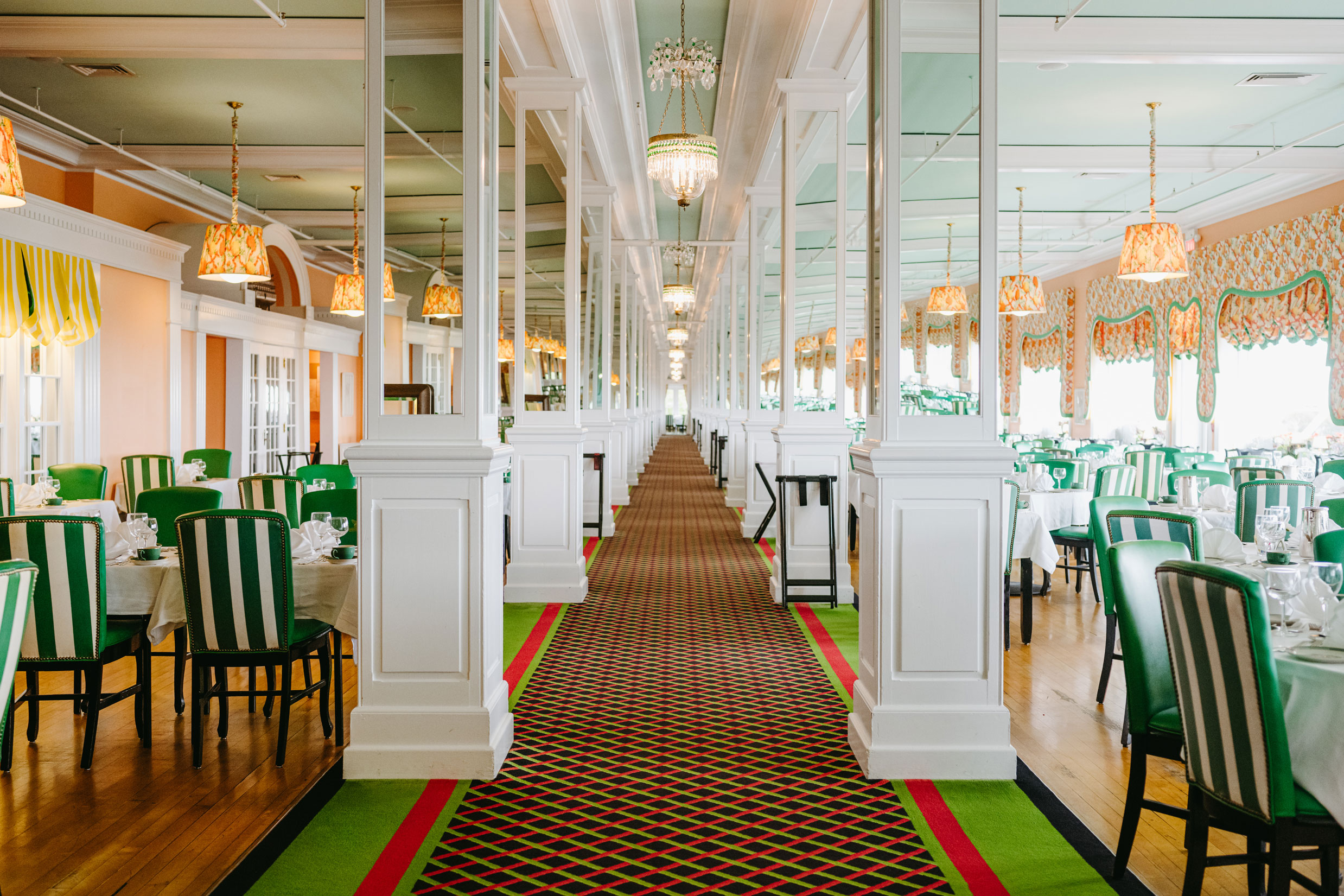 Image of The Main Dining Room with striped green and white chairs and mirrored pillars. Grand Hotel, a member of Historic Hotels since 2001, dates to 1886. It is located in Mackinac Island, Michigan.