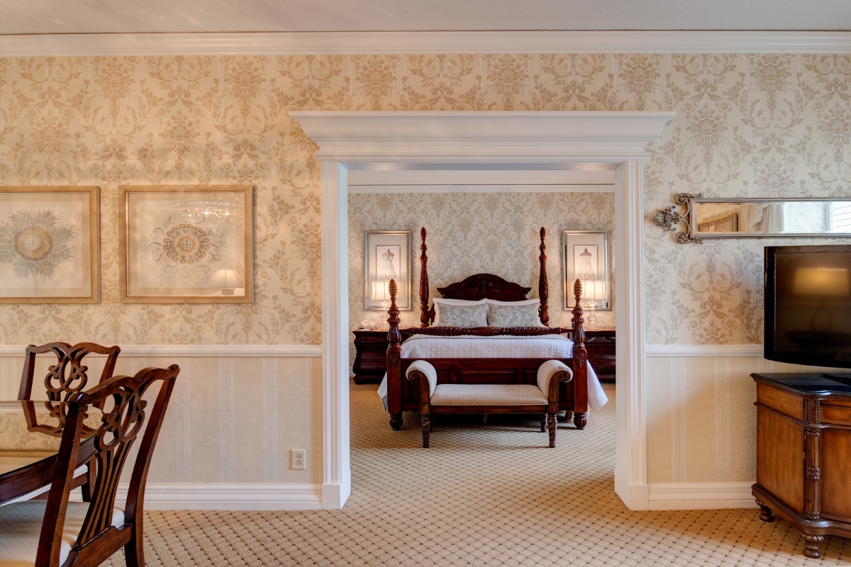 Image of the Dolley Madison Suite at The Nassau Inn (1756), a member of Historic Hotels of America since 2024. Pictured is a large bed through a door with ornate decor.