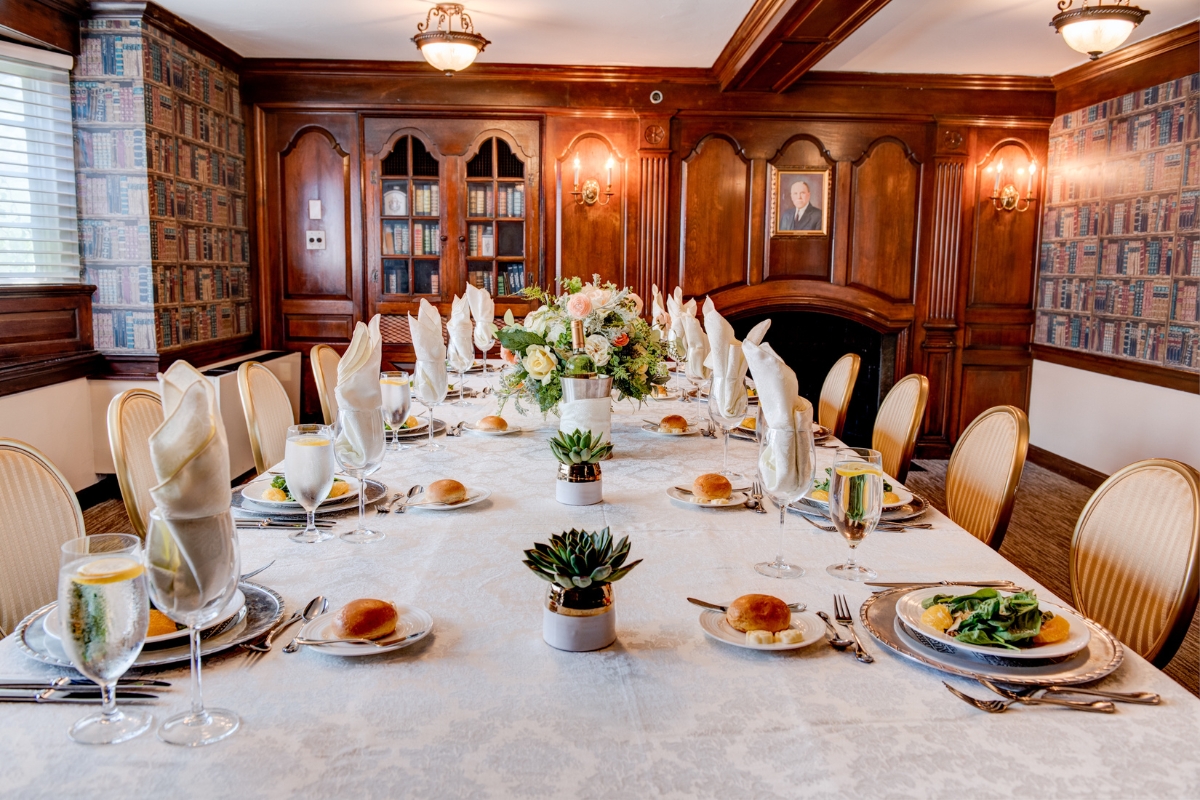Image of the Library Room at The Nassau Inn (1756), a member of Historic Hotels of America since 2024. Pictured is a long table set for a luncheon and surrounded by chairs.
