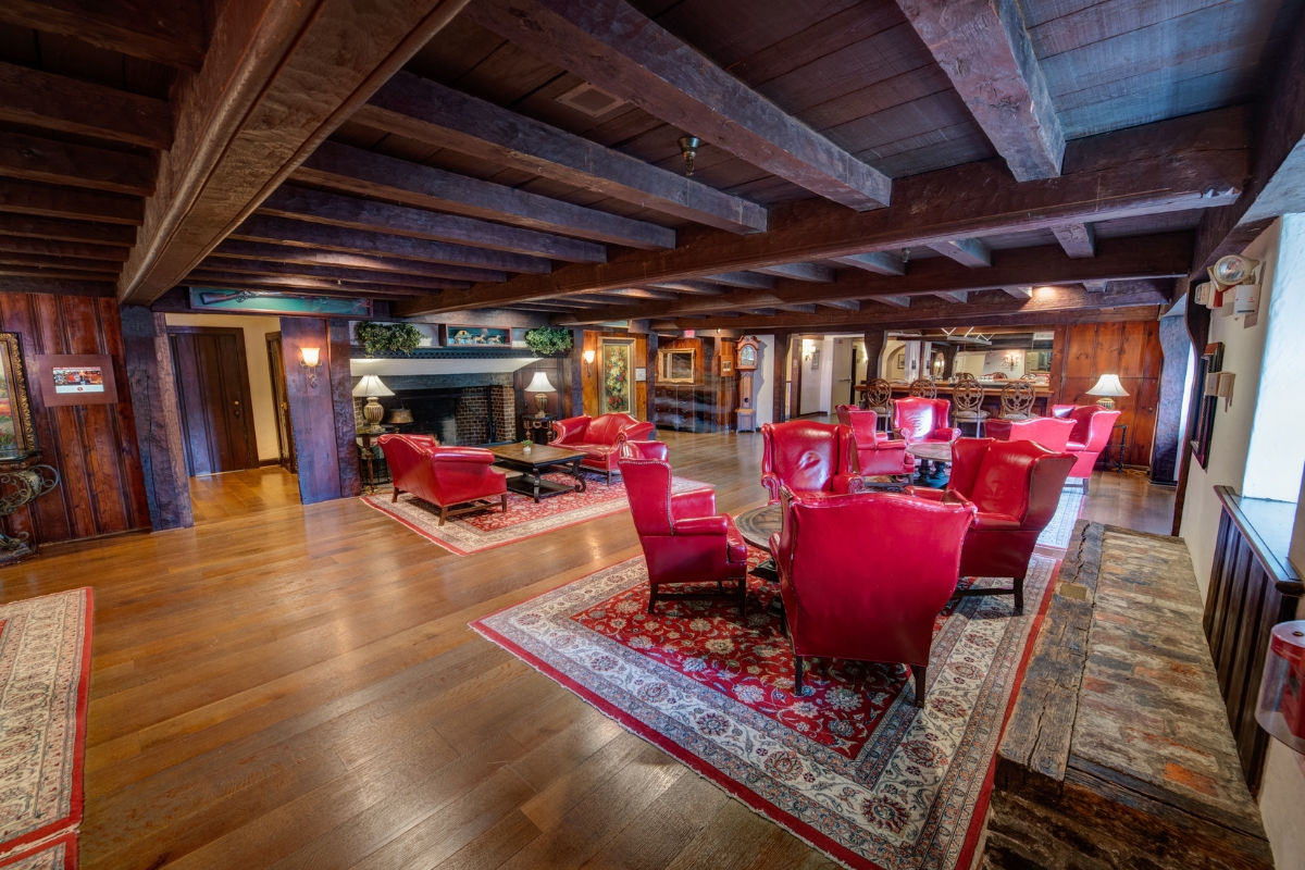 Image of the lobby at The Nassau Inn (1756), a member of Historic Hotels of America since 2024. Pictured are several red armchairs in a large room with ornate beams and carpets.