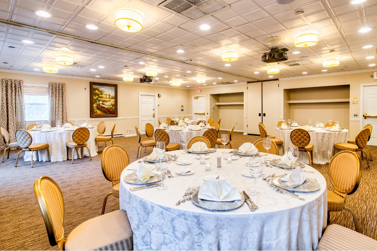 Image of the Nassau Rooms at The Nassau Inn (1756), a member of Historic Hotels of America since 2024. Pictured are several round, set tables in a large room.