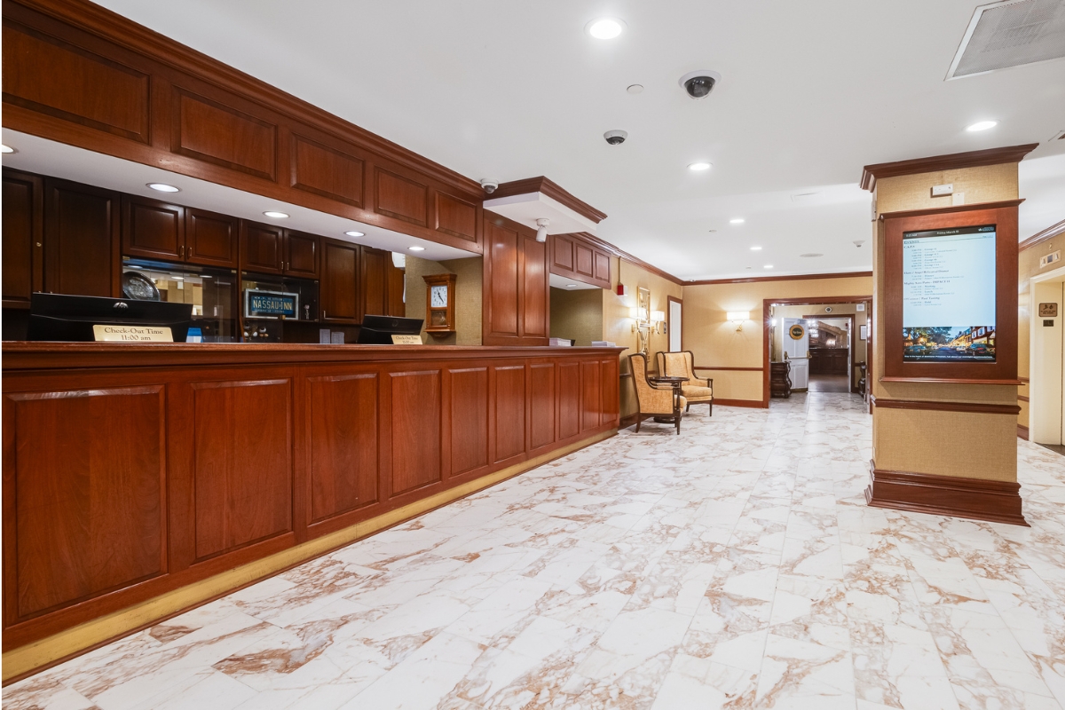 Image of the reception desk at The Nassau Inn (1756), a member of Historic Hotels of America since 2024. Pictured is a long wooden desk in a bright room with marble floors.