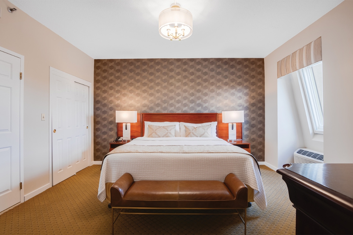 Image of a standard suite at The Nassau Inn (1756), a member of Historic Hotels of America since 2024. Pictured is a large bed and other furnishings.