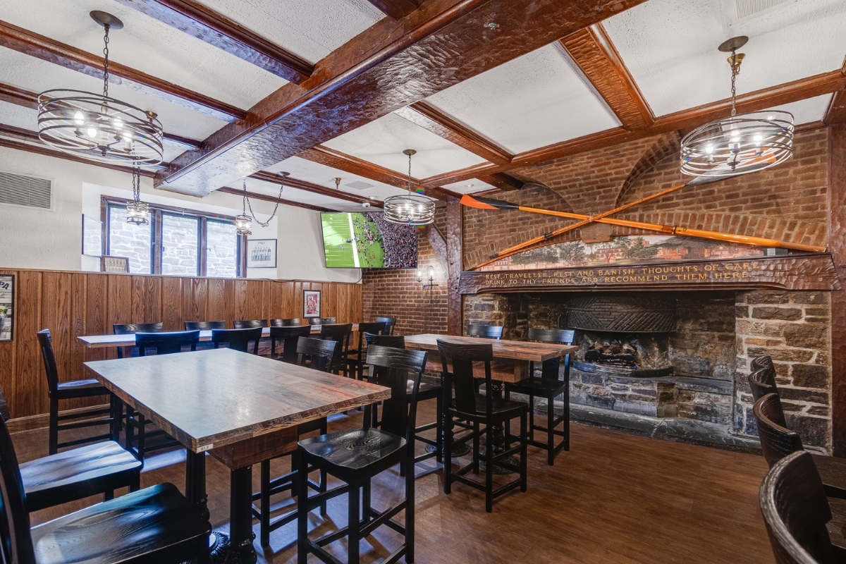 Image of the dining room at The Nassau Inn (1756), a member of Historic Hotels of America since 2024. Pictured are several tables with chairs in front of a fireplace.
