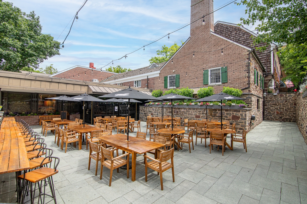 Image of the restaurant patio at The Nassau Inn (1756), a member of Historic Hotels of America since 2024. Pictured are several outdoor tables on a large patio.