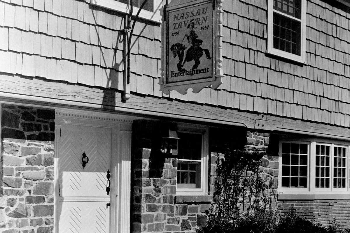 Historic image of the original entryway at the Nassau Inn (1756) a member of Historic Hotels of America since 2024. Pictured is a door and sign set in a stone wall.
