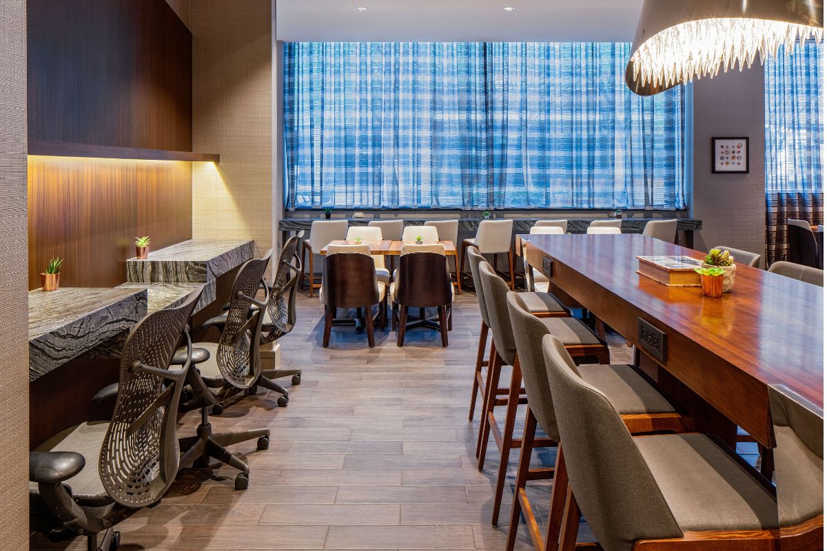 Image of cafe seating at Hilton Richmond Downtown (1885), a member of Historic Hotels of America since 2024. Pictured are several tables and a counter with chairs.