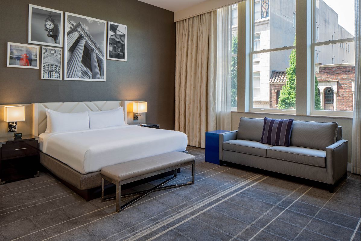 Image of a room at Hilton Richmond Downtown (1885), a member of Historic Hotels of America since 2024. Pictured is a large bed and couch in a bright room.