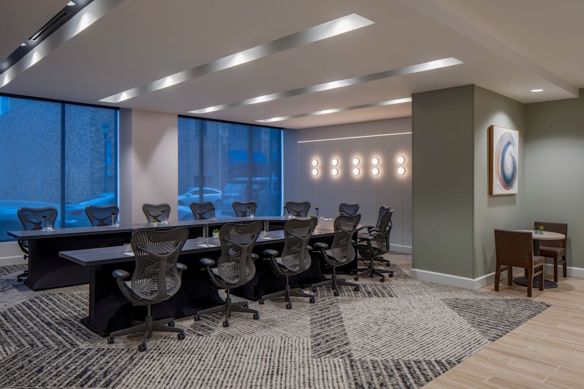Image of a meeting room at Hilton Richmond Downtown (1885), a member of Historic Hotels of America since 2024. Pictured are several rows of tables and chairs and expansive windows.
