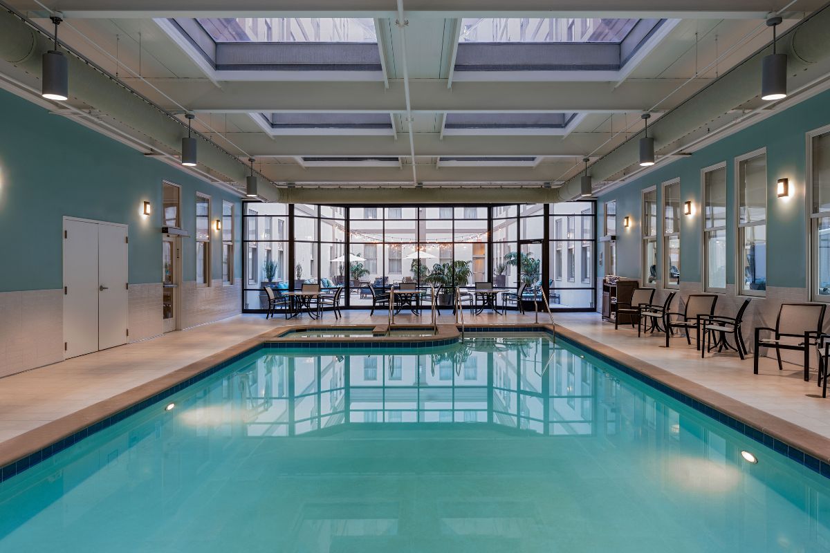 Image of the pool at Hilton Richmond Downtown (1885), a member of Historic Hotels of America since 2024. Pictured is a large pool in a room with skylights and lounge furniture.