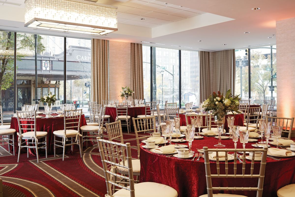 Image of a ballroom at Hilton Richmond Downtown (1885), a member of Historic Hotels of America since 2024. Pictured are set tables with chairs, windows and light fixtures.
