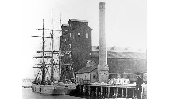 Historical image of West River Street in 1898. The waterfront site of the Riverside power plant was once home to diverse commercial activities, including this historic rice mill to the west of the power plant.